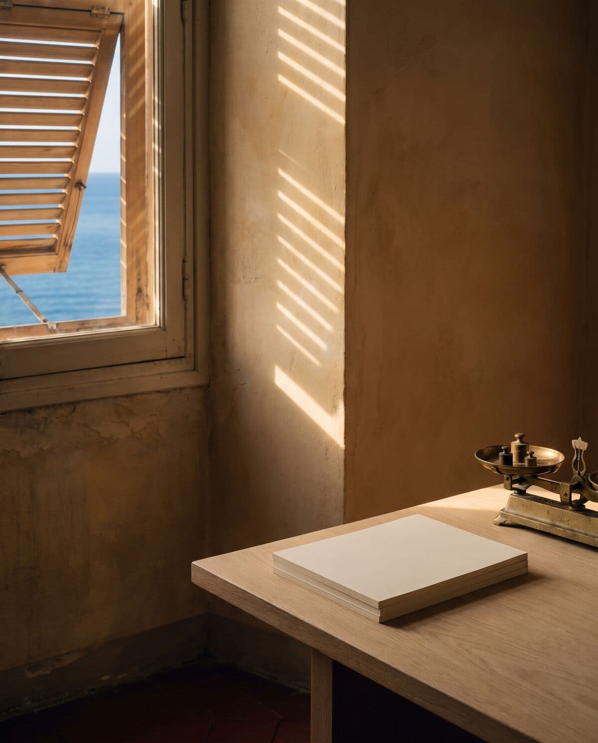 Studio inondato di luce in un palazzo d'epoca di Nizza: grande tavolo in rovere, bilancia in ottone, finestra ad arco aperta sul mare